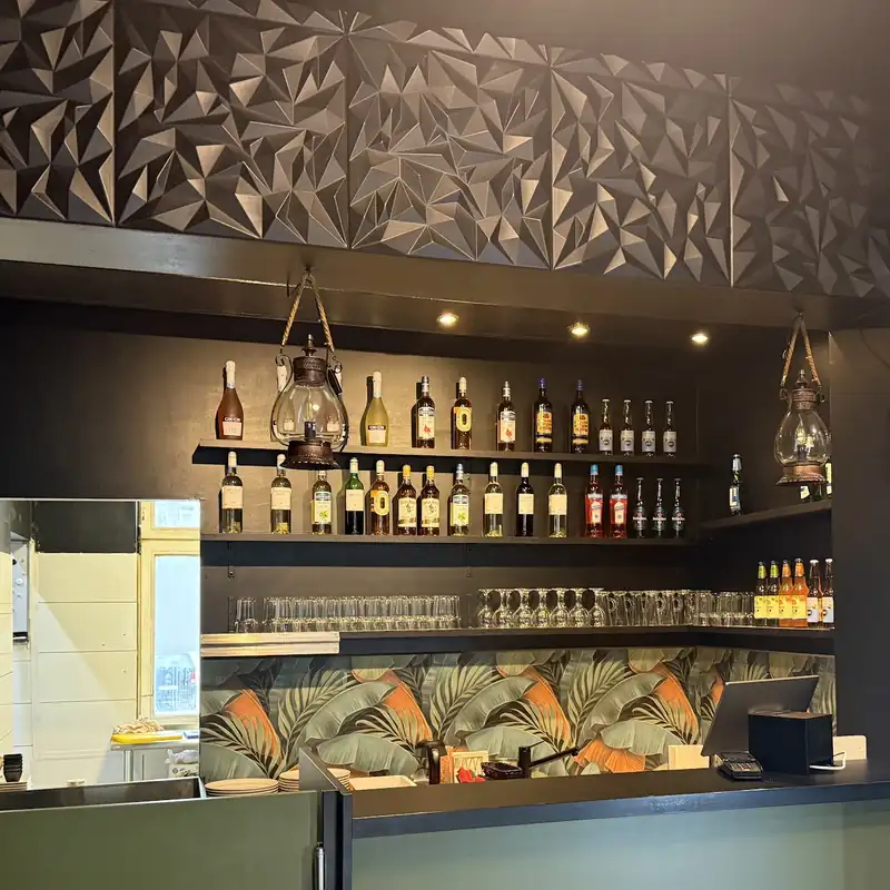 Bar lokalu z ciemną, przestrzenną ścianą i półkami z butelkami