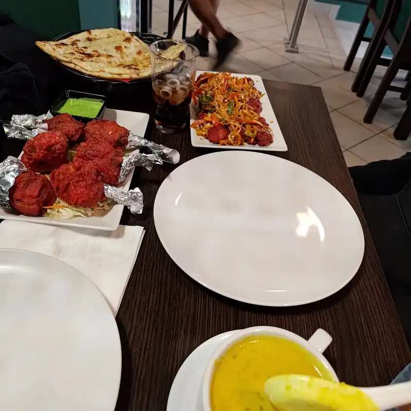 Stół z kurczakiem tandoori, naanem i miseczką zupy dal
