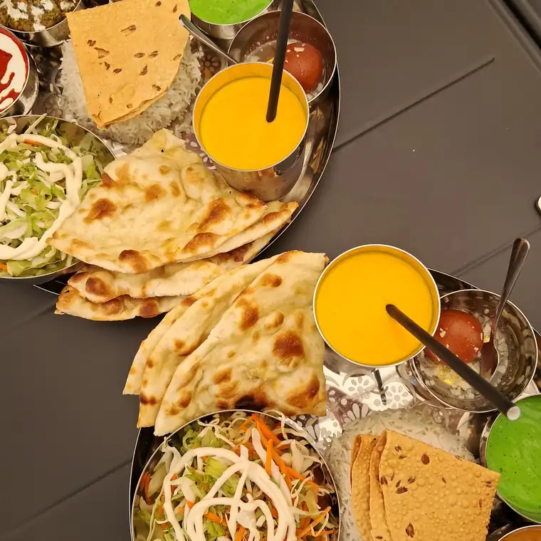 Talerz thali: miseczki z curry i dalem, surówka, naan i papad